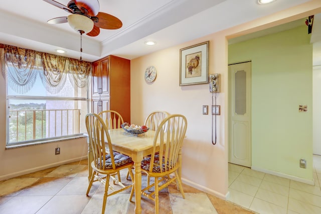 dining area featuring a tray ceiling, ceiling fan, ornamental molding, and light tile patterned flooring