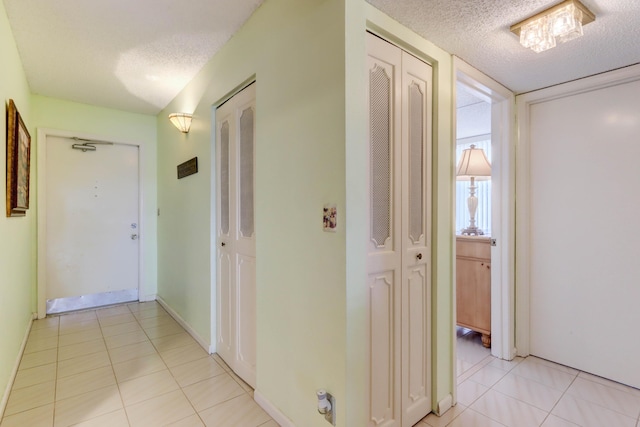 corridor with light tile patterned flooring and a textured ceiling