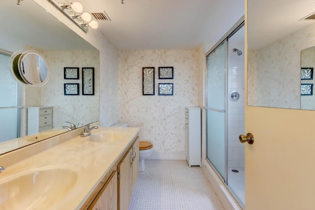 bathroom featuring tile patterned flooring, vanity, a shower with shower door, and toilet