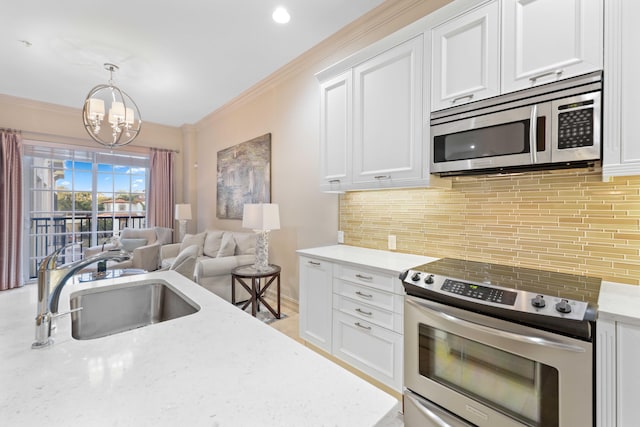 kitchen with light stone countertops, stainless steel appliances, sink, an inviting chandelier, and white cabinetry