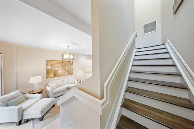 staircase featuring crown molding and a notable chandelier