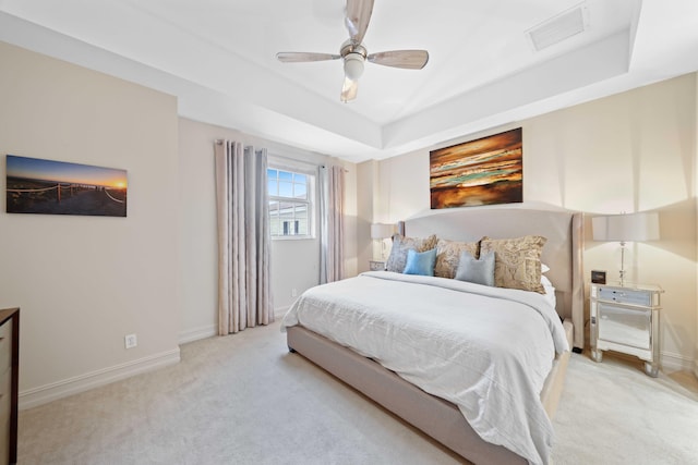 carpeted bedroom featuring a raised ceiling and ceiling fan