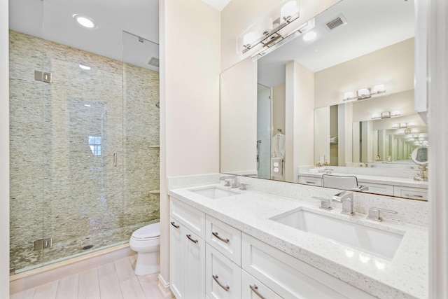 bathroom featuring a shower with door, vanity, and toilet