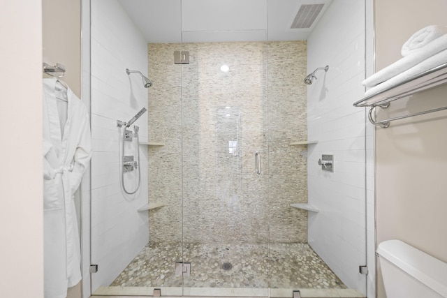 bathroom with a shower with shower door and toilet