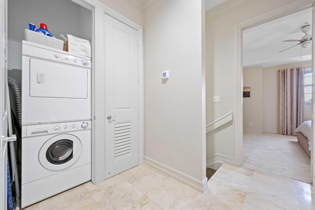 laundry room featuring ceiling fan, light colored carpet, stacked washer and clothes dryer, and ornamental molding