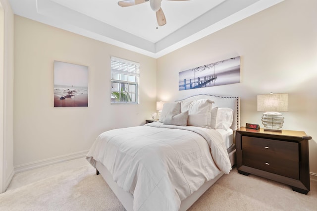 carpeted bedroom featuring ceiling fan and a tray ceiling