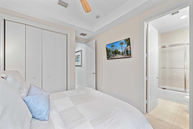 bedroom with light tile patterned floors, a closet, ensuite bath, and ceiling fan