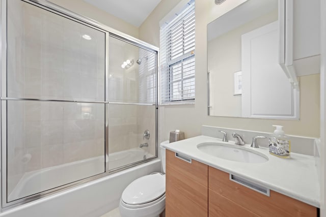 full bathroom with vanity, bath / shower combo with glass door, and toilet