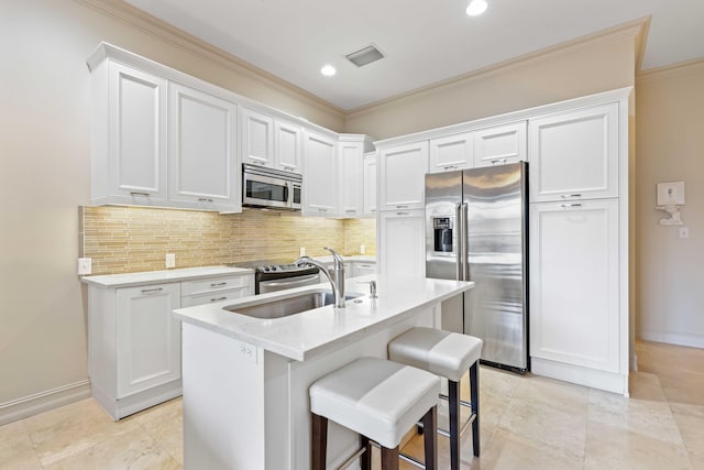 kitchen with sink, an island with sink, tasteful backsplash, white cabinetry, and stainless steel appliances