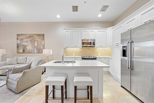 kitchen with appliances with stainless steel finishes, a breakfast bar, crown molding, sink, and white cabinets