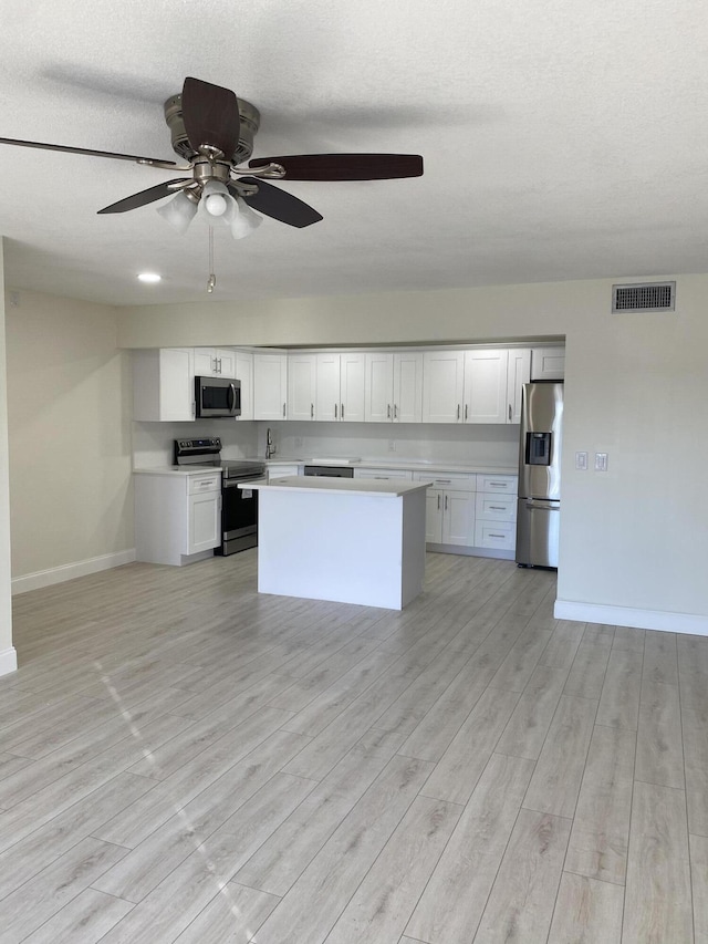 kitchen featuring stainless steel appliances, light hardwood / wood-style flooring, white cabinetry, and a center island