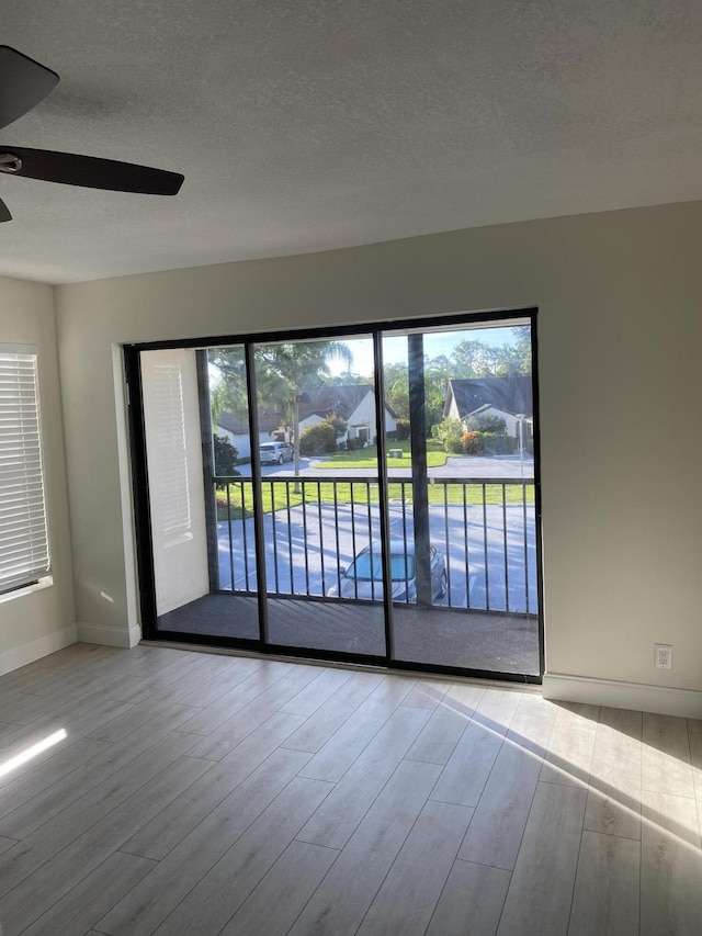 spare room with light wood-type flooring, ceiling fan, and a healthy amount of sunlight