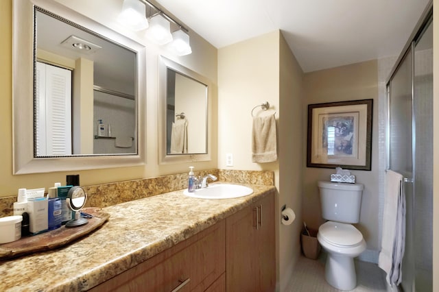 bathroom with vanity, toilet, and a shower with door