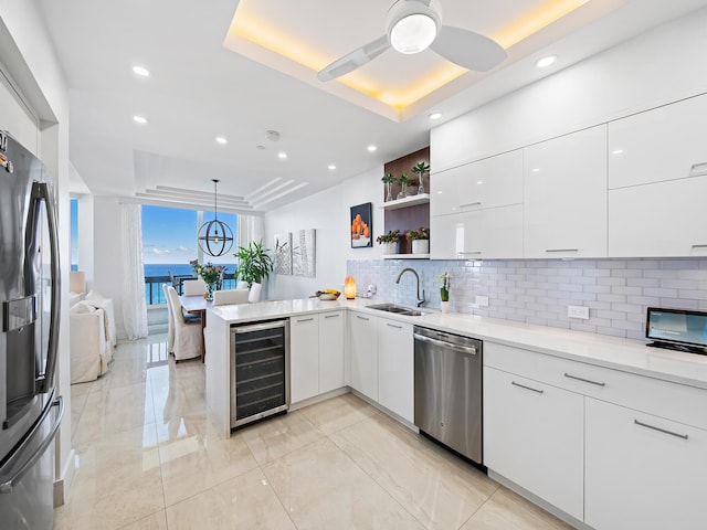 kitchen with stainless steel appliances, a raised ceiling, pendant lighting, and white cabinets