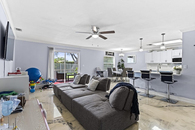 living room with ceiling fan with notable chandelier, crown molding, and sink