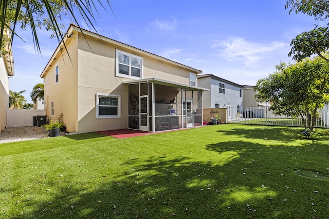 rear view of house featuring a lawn and a sunroom