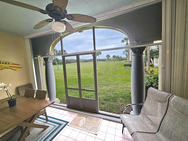 sunroom / solarium featuring ceiling fan and a rural view