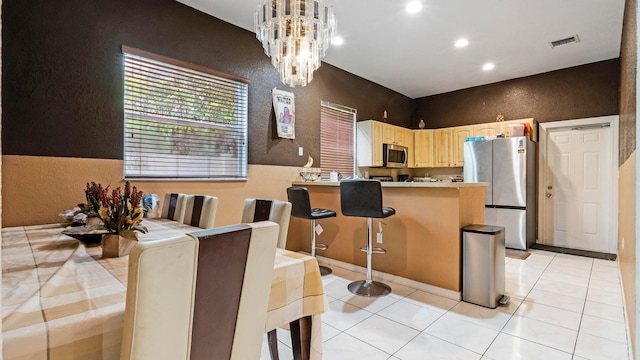 kitchen with a breakfast bar area, light tile patterned flooring, stainless steel appliances, and a notable chandelier