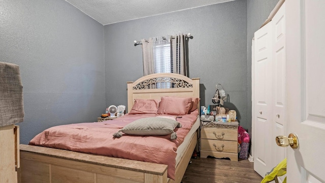 bedroom with dark hardwood / wood-style flooring, a textured ceiling, and a closet