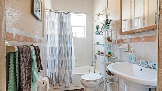 full bathroom with toilet, tile walls, shower / bath combo with shower curtain, and sink