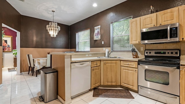 kitchen with sink, hanging light fixtures, light tile patterned flooring, stainless steel appliances, and a chandelier