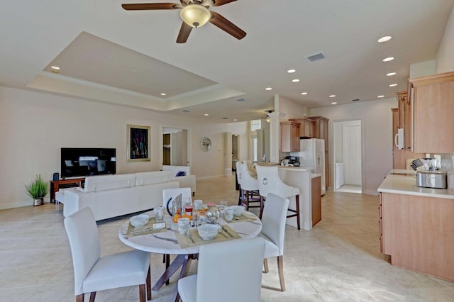 dining area with ceiling fan, light tile patterned floors, and a tray ceiling