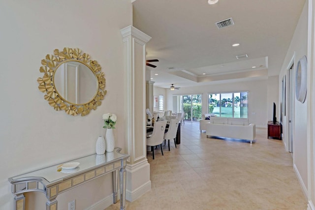 hallway featuring light tile patterned floors and a tray ceiling