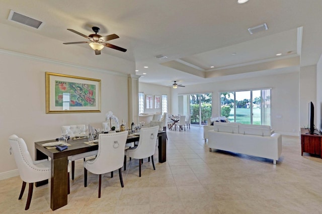 tiled dining room featuring a tray ceiling, ceiling fan, and ornamental molding