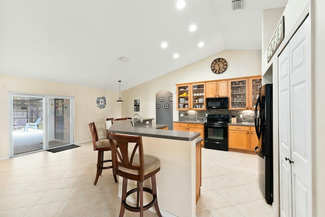 kitchen featuring hanging light fixtures, a kitchen breakfast bar, tasteful backsplash, black appliances, and vaulted ceiling