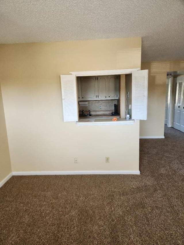 kitchen featuring decorative backsplash, dark carpet, and a textured ceiling