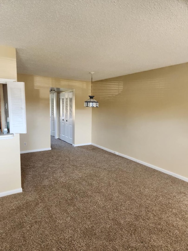 empty room featuring dark carpet and a textured ceiling