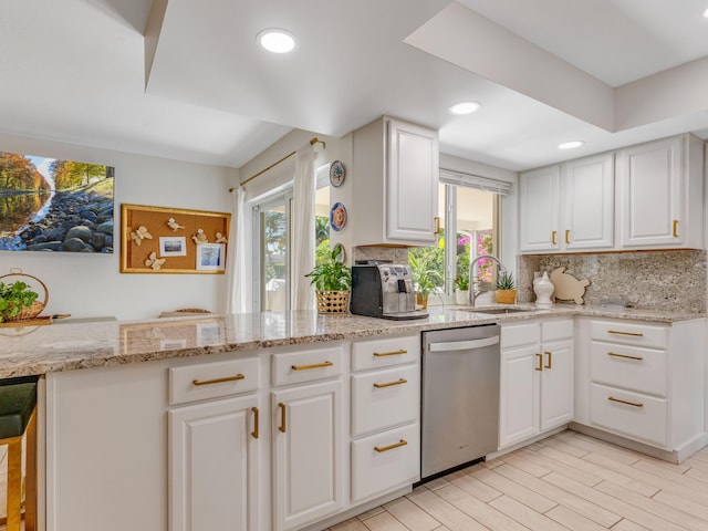 kitchen with sink, stainless steel dishwasher, kitchen peninsula, and white cabinets