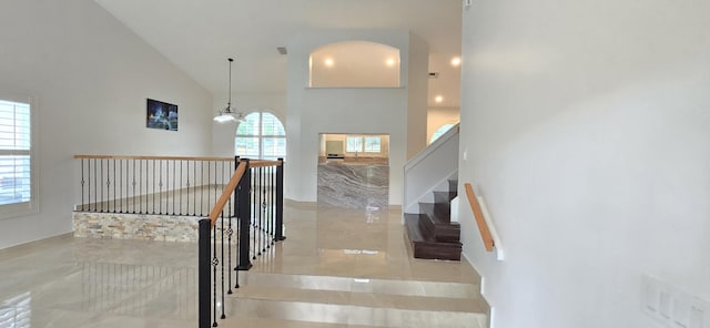 staircase featuring high vaulted ceiling and a chandelier