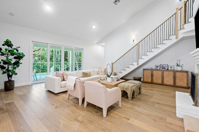 living room featuring high vaulted ceiling, light wood-type flooring, and a fireplace