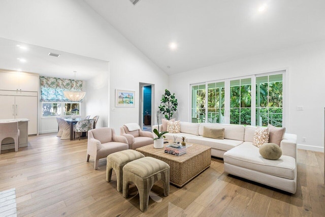 living room with a wealth of natural light, high vaulted ceiling, and light wood-type flooring