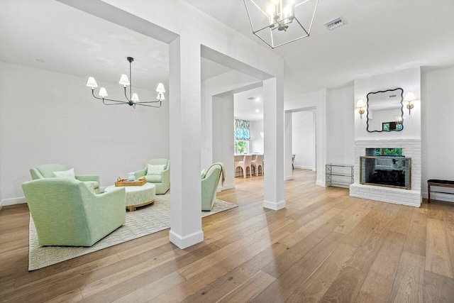 living room featuring an inviting chandelier, wood-type flooring, and a fireplace