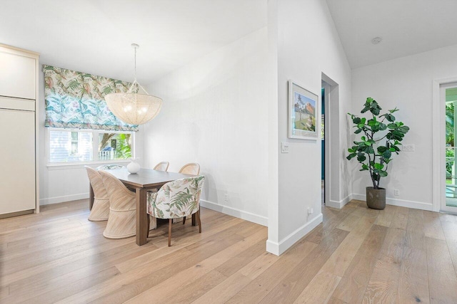 dining room featuring an inviting chandelier, lofted ceiling, and light hardwood / wood-style floors