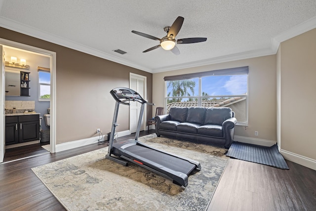 exercise room with ceiling fan, ornamental molding, dark hardwood / wood-style floors, and a textured ceiling