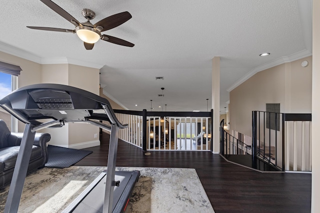 workout area with hardwood / wood-style flooring, ornamental molding, vaulted ceiling, and a textured ceiling