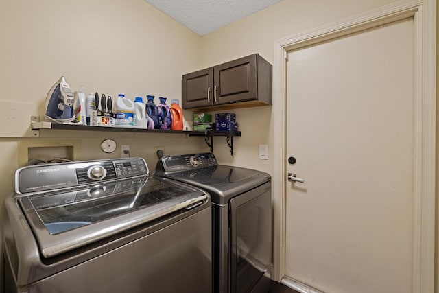 clothes washing area with cabinets, washing machine and clothes dryer, and a textured ceiling