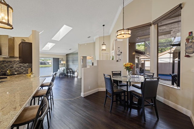 dining room with crown molding, dark wood-type flooring, and lofted ceiling with skylight