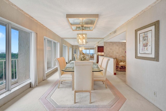 carpeted dining area with a notable chandelier, a wealth of natural light, and ornamental molding