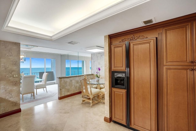 kitchen featuring a raised ceiling, ornamental molding, and a water view