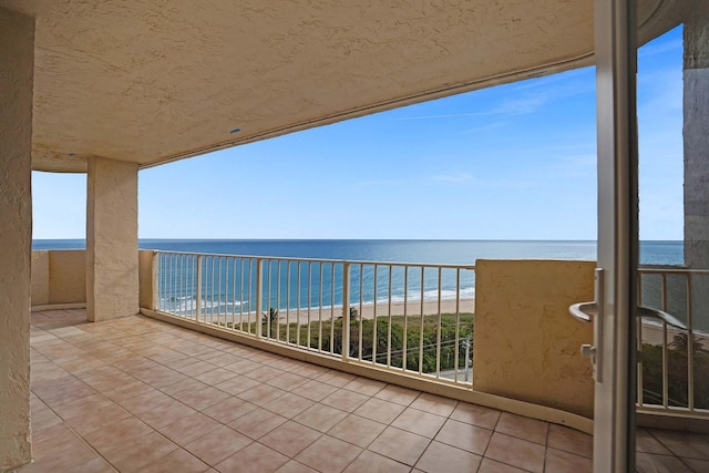 balcony with a water view and a view of the beach