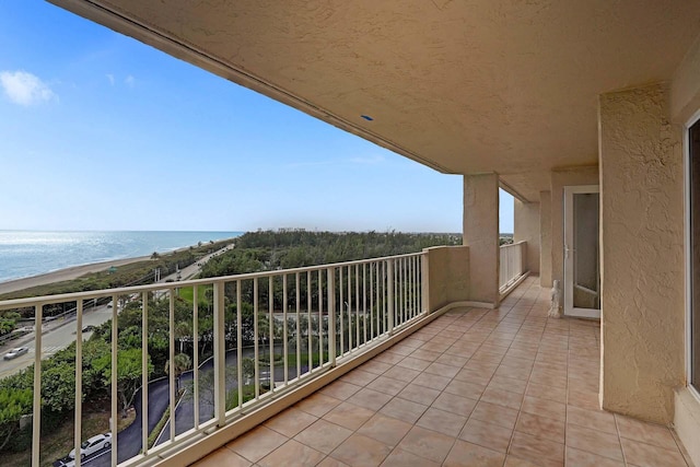 balcony with a water view and a view of the beach