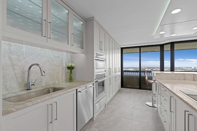 1900 Consulate Pl Unit 1902, West Palm Beach, FL 33401 - kitchen featuring sink, dishwasher, backsplash, light stone counters, and white cabinets