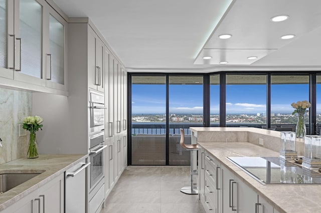 1900 Consulate Pl Unit 1902, West Palm Beach, FL 33401 - kitchen with light tile patterned flooring, sink, white cabinets, expansive windows, and stainless steel appliances