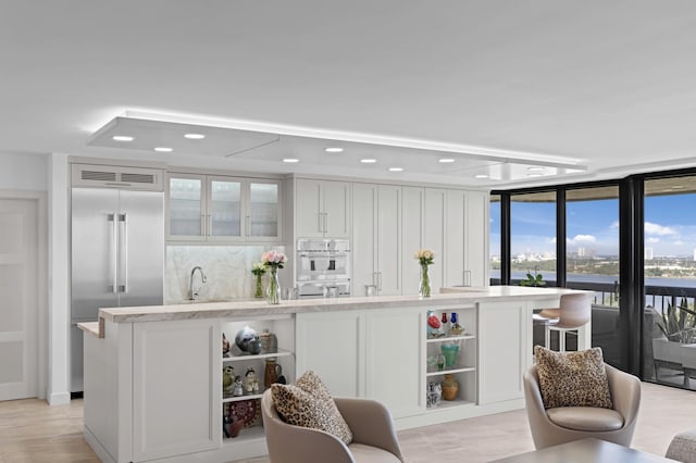 1900 Consulate Pl Unit 1902, West Palm Beach, FL 33401 - bar with floor to ceiling windows, light hardwood / wood-style floors, built in fridge, and white cabinets