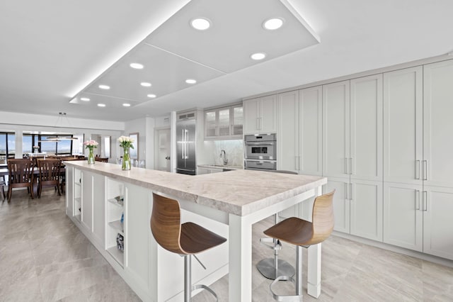 1900 Consulate Pl Unit 1902, West Palm Beach, FL 33401 - kitchen with stainless steel appliances, white cabinetry, a breakfast bar, and sink