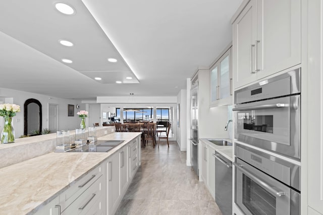 1900 Consulate Pl Unit 1902, West Palm Beach, FL 33401 - kitchen featuring sink, light stone countertops, white cabinets, and appliances with stainless steel finishes